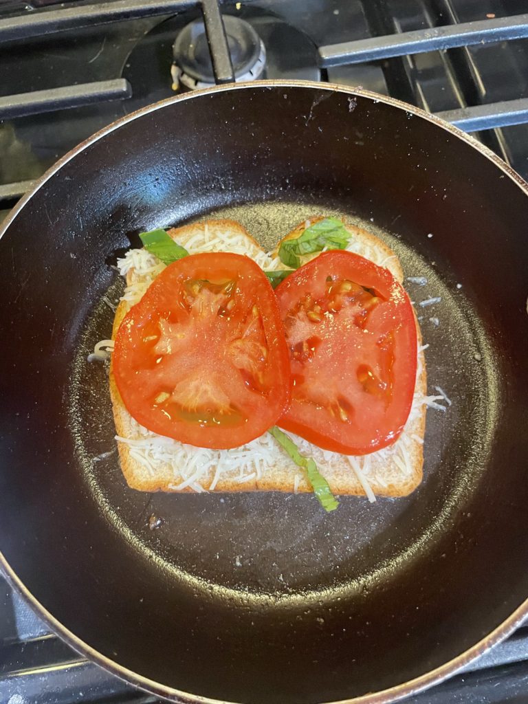 Bread with cheese, basil, and tomato on it.